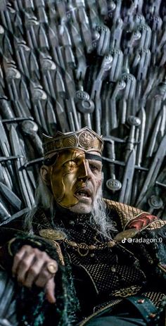 a man sitting on the iron throne with his hands in his pockets and wearing gold paint