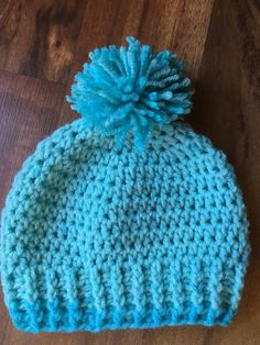 a crocheted hat with a blue pom - pom