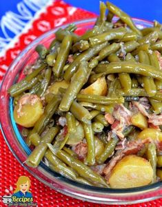 green beans and potatoes in a glass bowl on a red tablecloth with a spoon