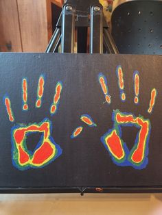 two hand prints on a black board with red and blue colors