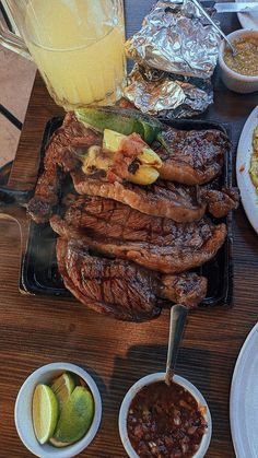 the steak is prepared and ready to be served with salsa, limes, and other condiments