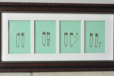 three framed pictures with metal clips on them in a brown and white frame against a green wall