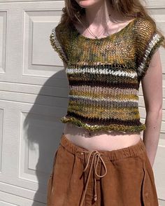 a woman standing in front of a garage door wearing a knitted top and skirt