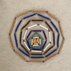 a close up of a beaded object on a white surface with blue, yellow and brown beads