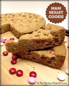 two brownies with m & m cookies on top and candy in the middle, sitting on a cutting board