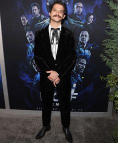 a man in a tuxedo and bow tie standing in front of a movie poster