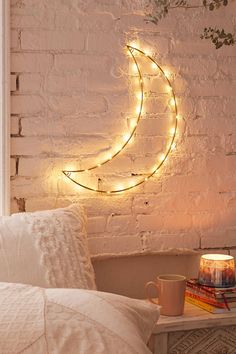 a white brick wall with a crescent shaped light hanging over the bed and coffee cup on the side table