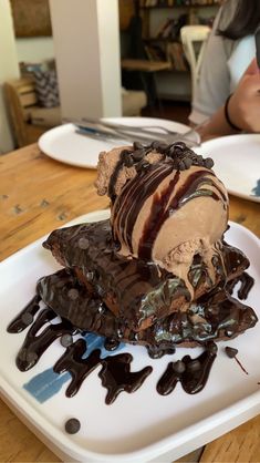 a white plate topped with an ice cream sundae covered in chocolate and caramel