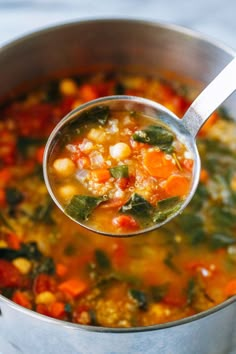 a ladle full of vegetable soup being held by a spoon