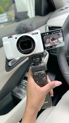 a person holding a camera in their hand while sitting in the driver's seat