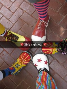 four pairs of feet with colorful socks and striped socks on them, standing next to each other