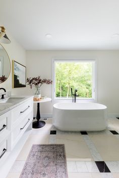 a bathroom with a tub, sink and large mirror in it's center window