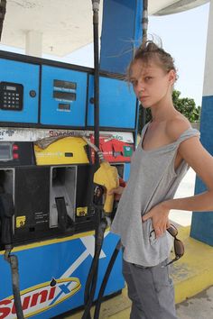 a woman standing next to a gas pump