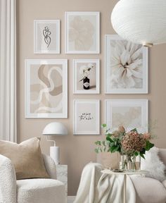 a living room filled with white furniture and pictures on the wall above it's coffee table