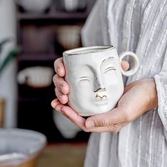 a woman holding a white mug with a face on it