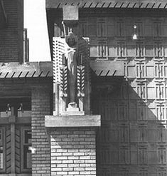 an old black and white photo of a building with a statue on it's side