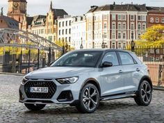 the new audi q3 suv is parked on a cobblestone street in front of some buildings