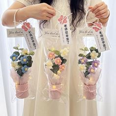 a woman is holding three bags with flowers in them and tags attached to the handles