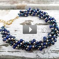 a blue beaded bracelet on top of a piece of drift wood with a gold plated clasp