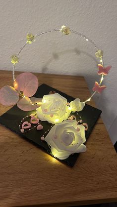 a lighted rose sits on top of a card with butterflies around it and the letters love is spelled in pink