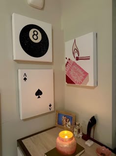 two cards are hanging on the wall above a table with a candle and some pictures