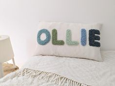 a pillow that says ollie on it sitting on top of a bed next to a lamp