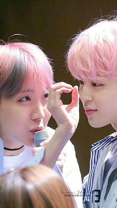 two young men with pink hair standing next to each other in front of a microphone