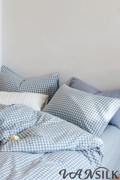 an unmade bed with blue and white checkered sheets