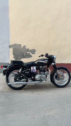 a black motorcycle parked in front of a wall with graffiti on it's side