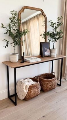 a wooden table topped with a mirror next to two baskets filled with plants and potted plants