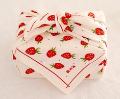 four napkins with strawberries on them are folded up and tied together, sitting on a white surface