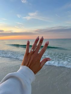 a woman's hand on the beach at sunset