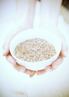 a person holding a white bowl filled with brown rice