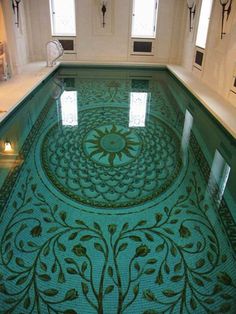 an indoor swimming pool with intricate designs on the floor