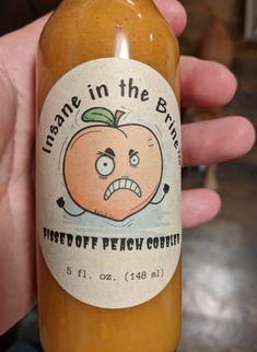 a hand holding a bottle of peanut butter with an angry face on it's label