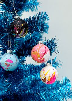 three ornaments hanging from a blue christmas tree