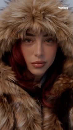 a woman with red hair wearing a fur coat and looking at the camera, close up