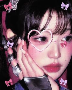 a girl with heart shaped glasses on her face and pink bows around her hair, holding her hands to her face