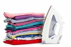 a stack of folded clothes next to an iron