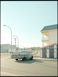 an old pick up truck is parked in front of a building on the side of the road