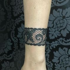 a woman's arm with a black lace bracelet on her left wrist and an intricate design