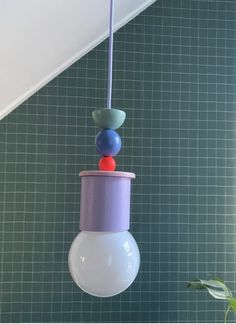 a light fixture hanging from the ceiling in a room with green tiles on the wall