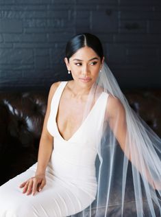 a woman sitting on top of a couch wearing a white dress and a veil over her head