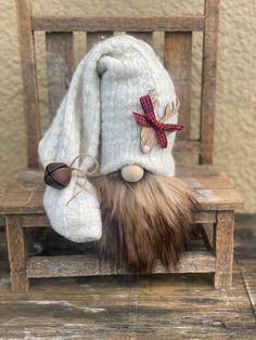 a stuffed animal sitting on top of a wooden chair next to a white sweater and hat