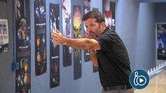 a man pointing at pictures on the wall in an indoor bowling alley with his hand out