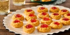 small cookies with jam on them sitting on a plate next to a glass of water