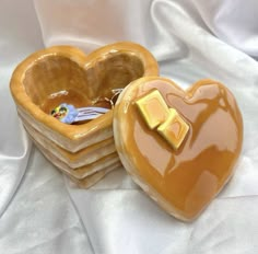 a heart shaped box with a golden bow on it sitting on a white cloth covered tablecloth