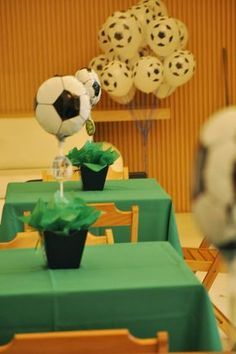 a table topped with green cloth covered tables and soccer balls on top of each table