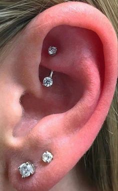 a woman's ear with three diamond studs