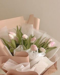 a bouquet of pink tulips and white roses in a brown paper box on a table